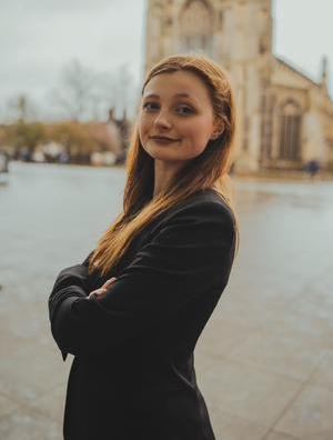 Lucy Barnes standing in side profile with her arms crossed