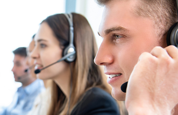 Man smiling while talking through a headset on his head.