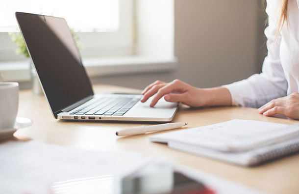 Woman typing on a laptop.