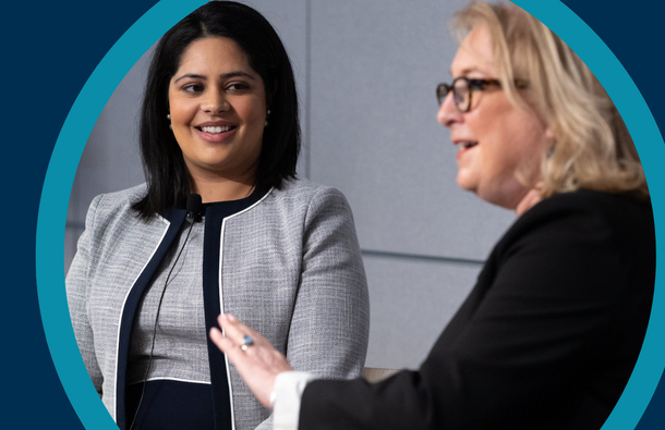 A graphic frame around a photo of two panellists talking on stage at an event